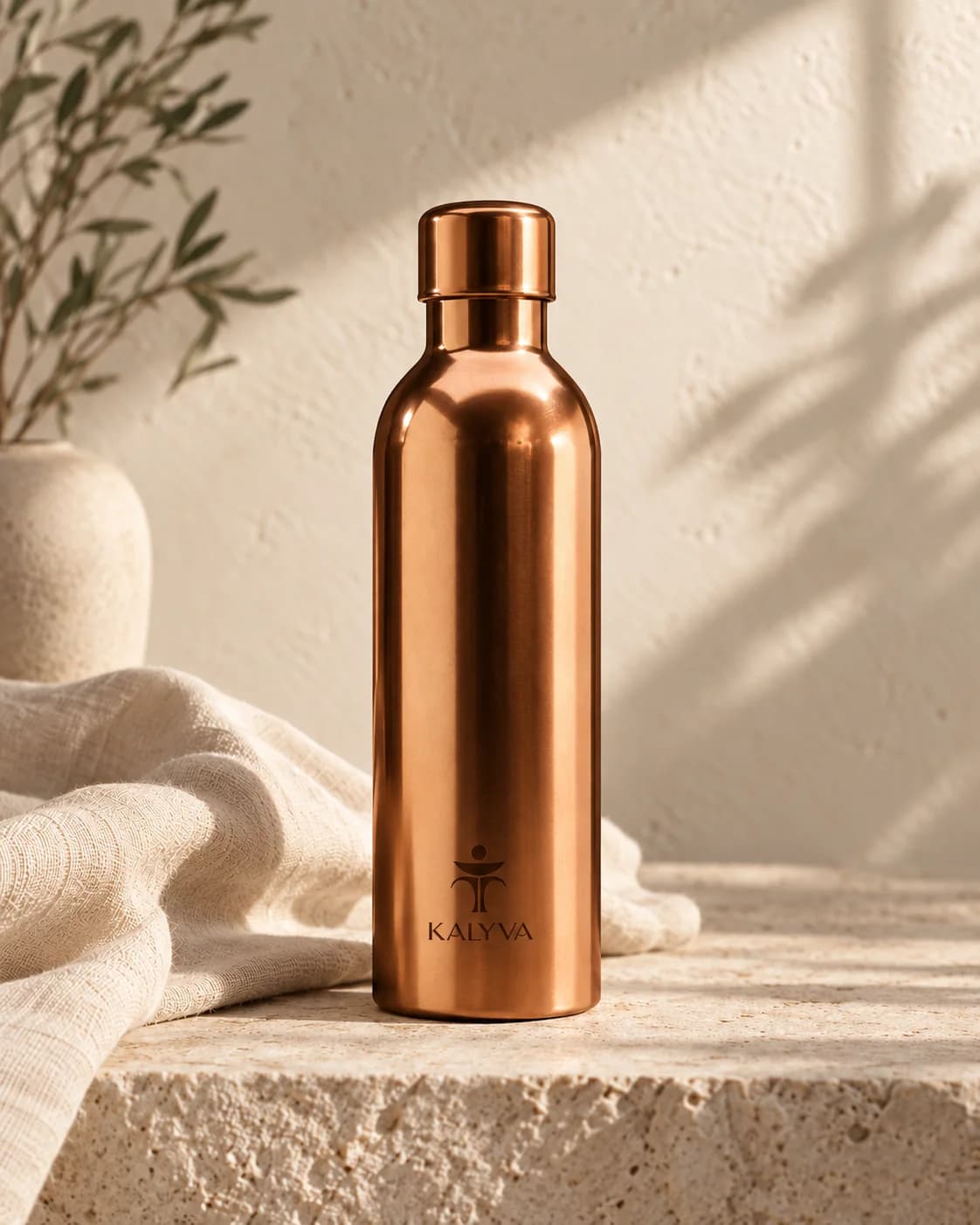 KALYVA copper bottle beside ivory linen